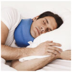 Man sover på sidan med blå sovkrage runt halsen