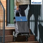 Scala Trappgående blå i trappa Andersen Scala Trappgående med Hera-väska i blått dras uppför en trappa på trestjärniga hjul