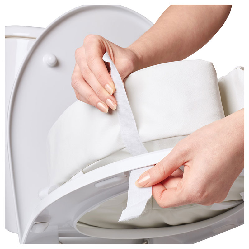 Hand drar i kardborreband på Vitility toalettkuddens överdrag